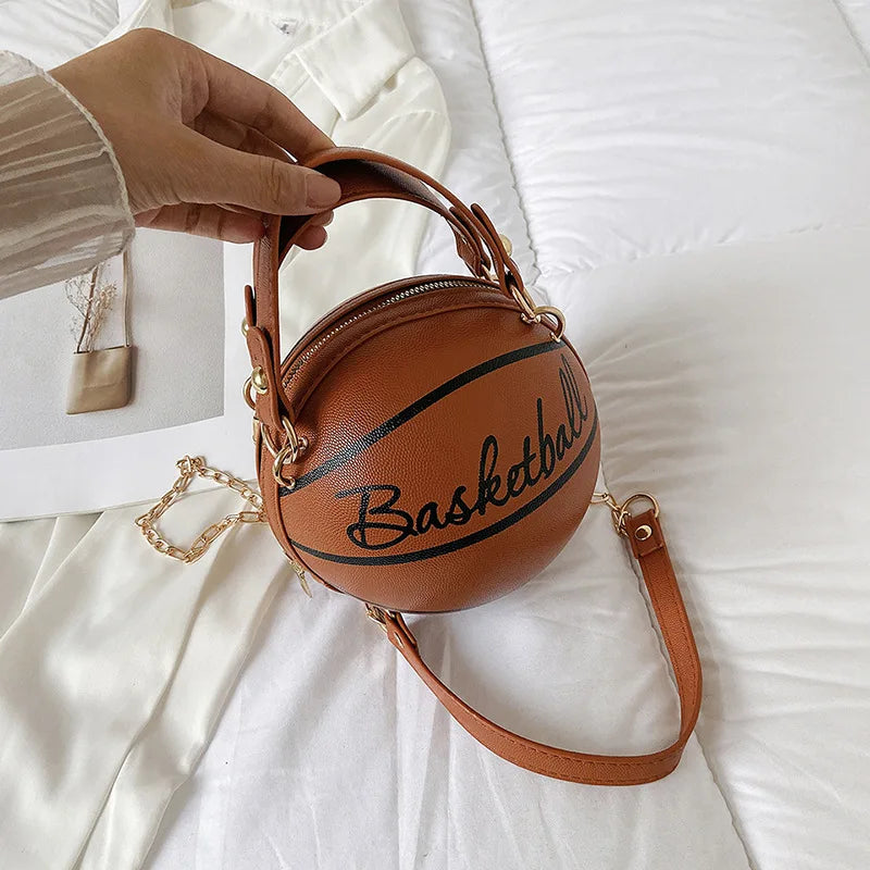 Basketball-shaped handbag with 'Basketball' text held by a hand on a white background