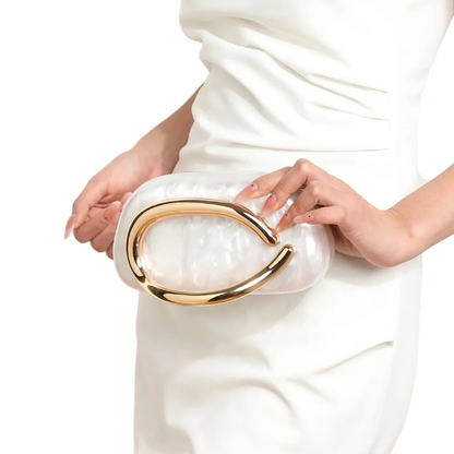White clutch with gold accents held by a person wearing a white dress.