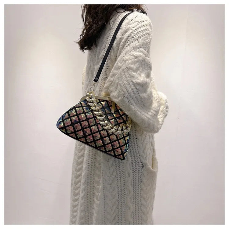 Person wearing a white knit sweater holding a patterned handbag against a plain background