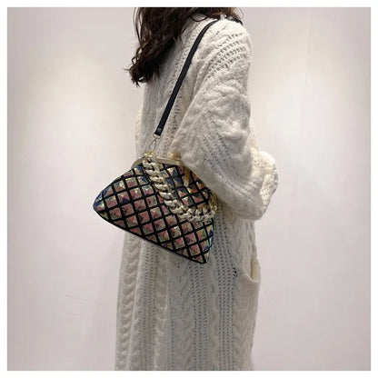 Person wearing a white knit sweater holding a patterned handbag against a plain background
