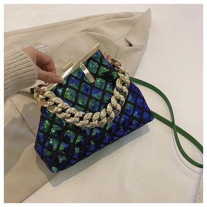 Handbag with blue and green pattern and gold chain handle held by a hand on a light background
