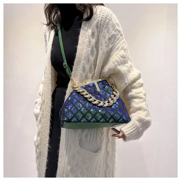 Person wearing a blue and green patterned handbag with a white cardigan.