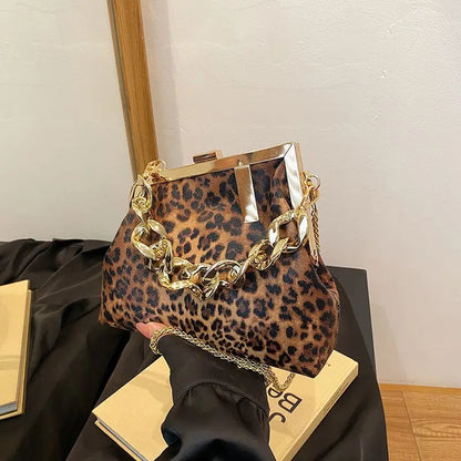 Carauana_UNIU_Leopard_Clutch with gold chain handle held by a hand on a black surface.