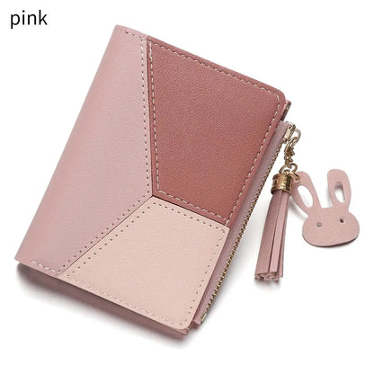 Pink wallet with a tassel and bunny charm on a white background