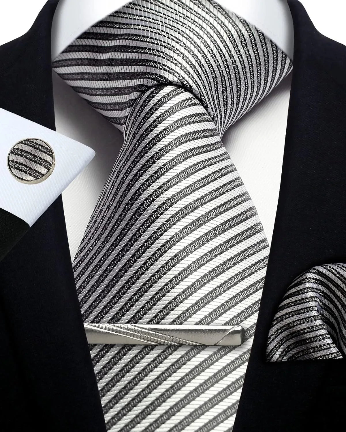 Black and white striped tie with matching cufflinks and tie clip on a black suit jacket.