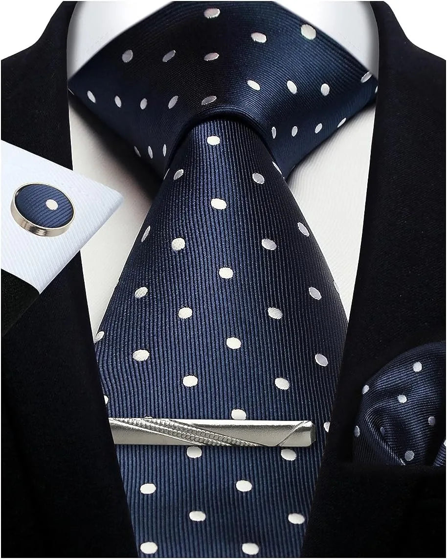 Navy blue tie with white polka dots, silver tie clip, and matching pocket square on a suit.